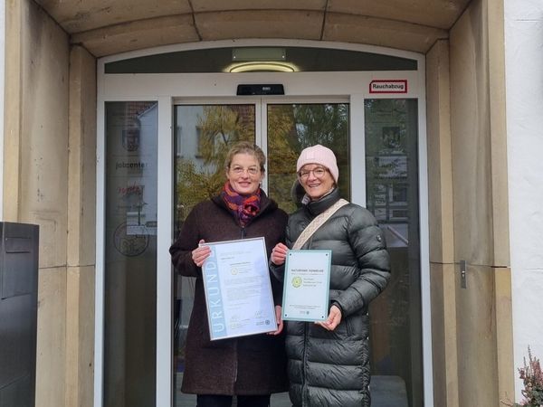 Zwei Personen halten eine Urkunde und eine Plakette