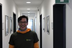 Das Bild zeigt Naturparkführer Roman Weber in grünem T-Shirt im Gang der Naturpark-Geschäftsstelle. Er hat kurzes volles Haar und trägt eine Brille.