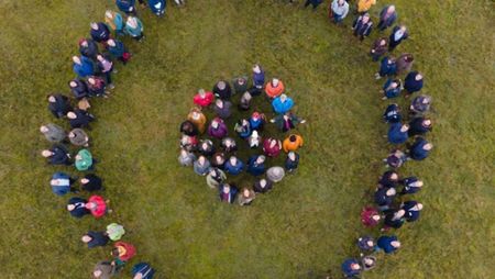 Eine große Gruppe von Menschen, die im Kreis steht, von oben fotografiert