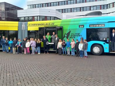 Eine Gruppe von Kindern steht vor dem bunten KlimaWandelBus