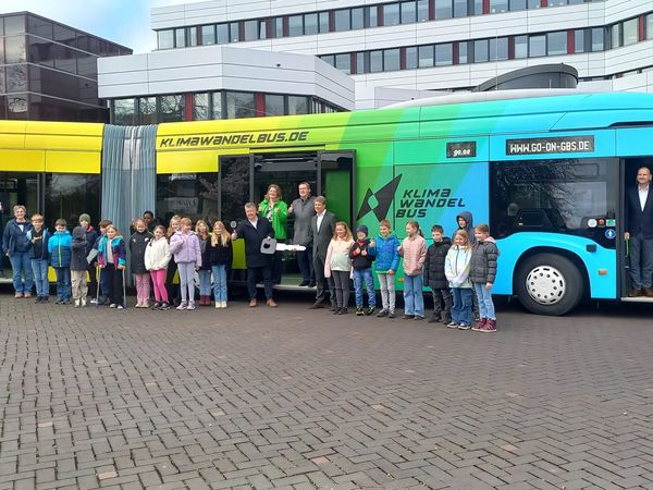 Eine Gruppe von Kindern steht vor dem bunten KlimaWandelBus