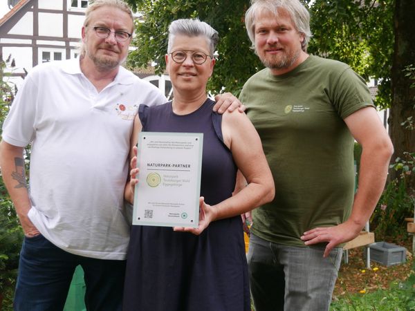 Drei Personen mit einer Urkunde in der Hand