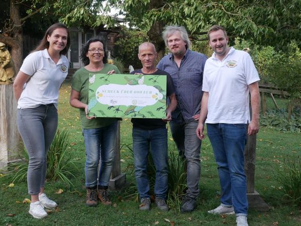 Fünf Personen halten einen großen Spendenscheck hoch