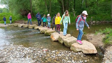 Kinder überqueren auf Trittsteinen die Berlebecke