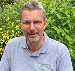 Das Bild zeigt Naturparkführer Reinhold Ix in grauem T-Shirt vor einer Hecke. Er hat kurzes graues Haar und einen Bart.
