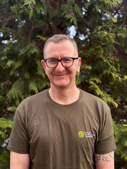 Das Bild zeigt Naturparkführer Rafael Koziel in grünem T-Shirt. Rafael hat sehr kurze dunkle Haare und eine Brille.