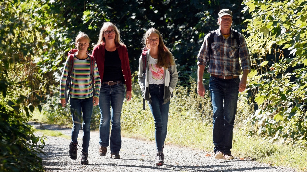 Eine Familie wandert auf einem steinigen Weg im Wald des Naturparks