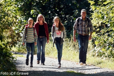 Eine Familie wandert auf einem steinigen Weg im Wald des Naturparks